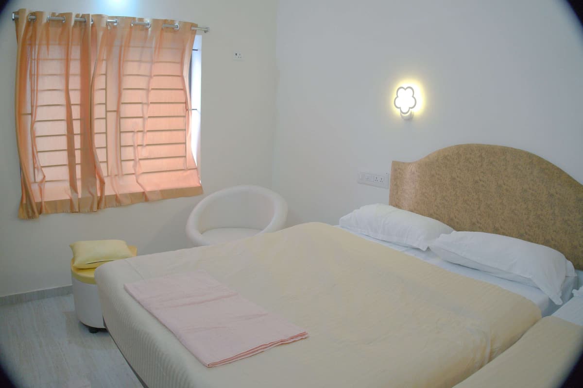 A neatly arranged bedroom with a bed, a chair, and a bedside table.