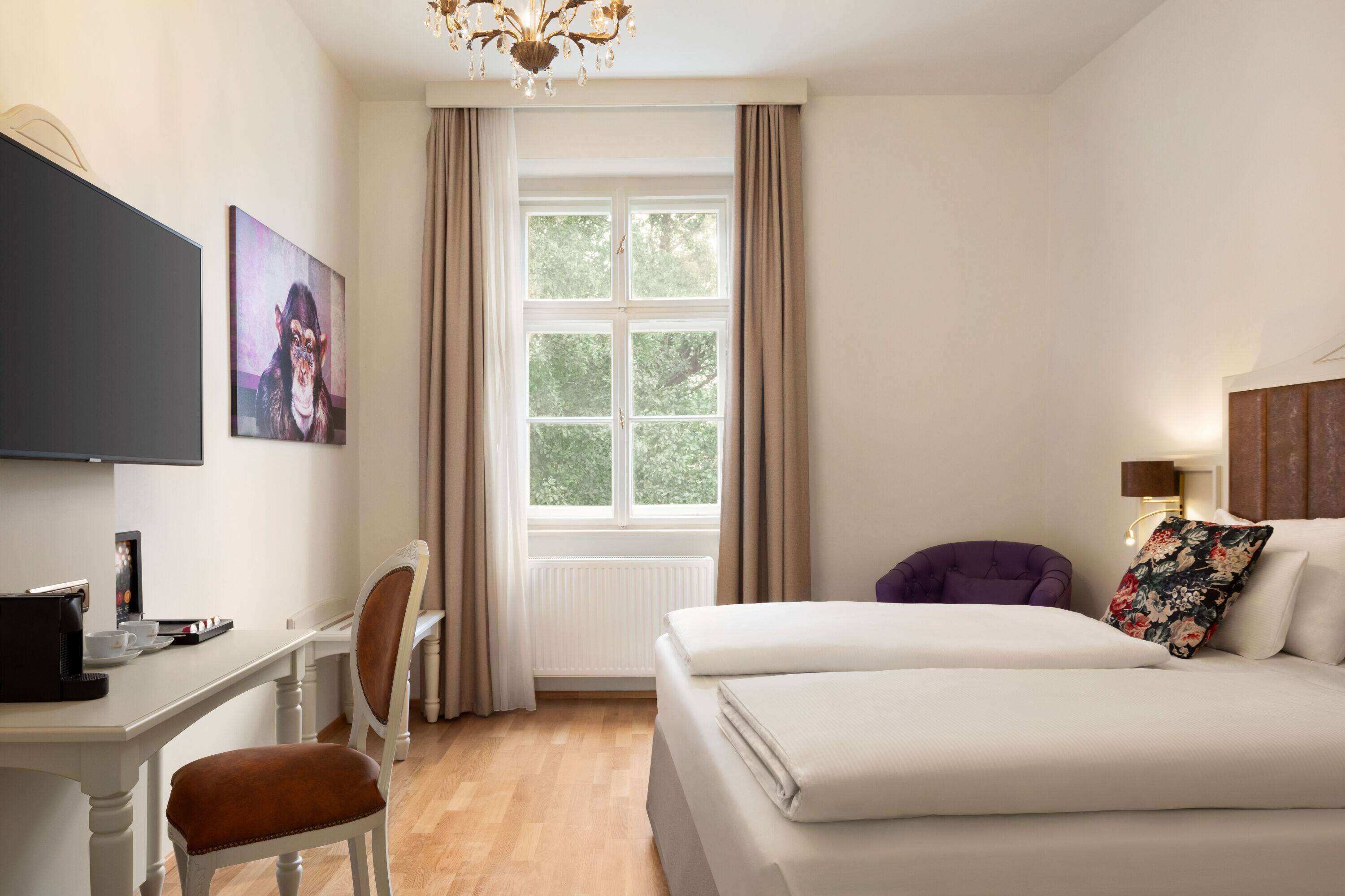 A hotel room with a bed, a desk, a chair, a television, and a window with curtains.