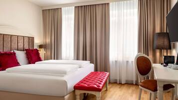 Ein Hotelzimmer mit einem großen Bett, einem kleinen Tisch, einem Stuhl und einer Bank.