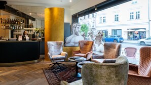 A hotel lobby with a bar area, comfortable seating, and large windows with city views. - DORMERO PaHo Wels (Wels)