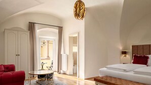 A modern hotel room with a bed, a red armchair, a round table, and a zebra-patterned rug. - DORMERO PaHo Wels (Wels)