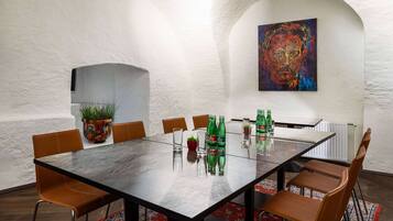 A dining area with a marble table, brown leather chairs, a colorful rug, and a potted plant.