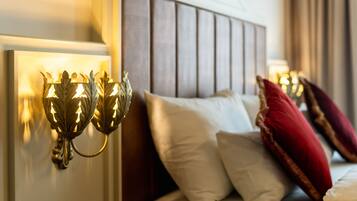 Une chambre à coucher avec une tête de lit en bois, un lit agrémenté d’oreillers blancs et rouges, et des appliques murales.