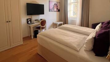 Ein Schlafzimmer mit Bett, Schreibtisch, Stuhl, Fernseher und Fenster.