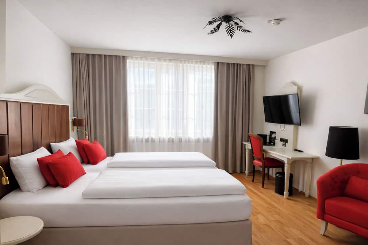 Una habitación de hotel con cama doble, escritorio, silla, televisor y ventilador de techo.
