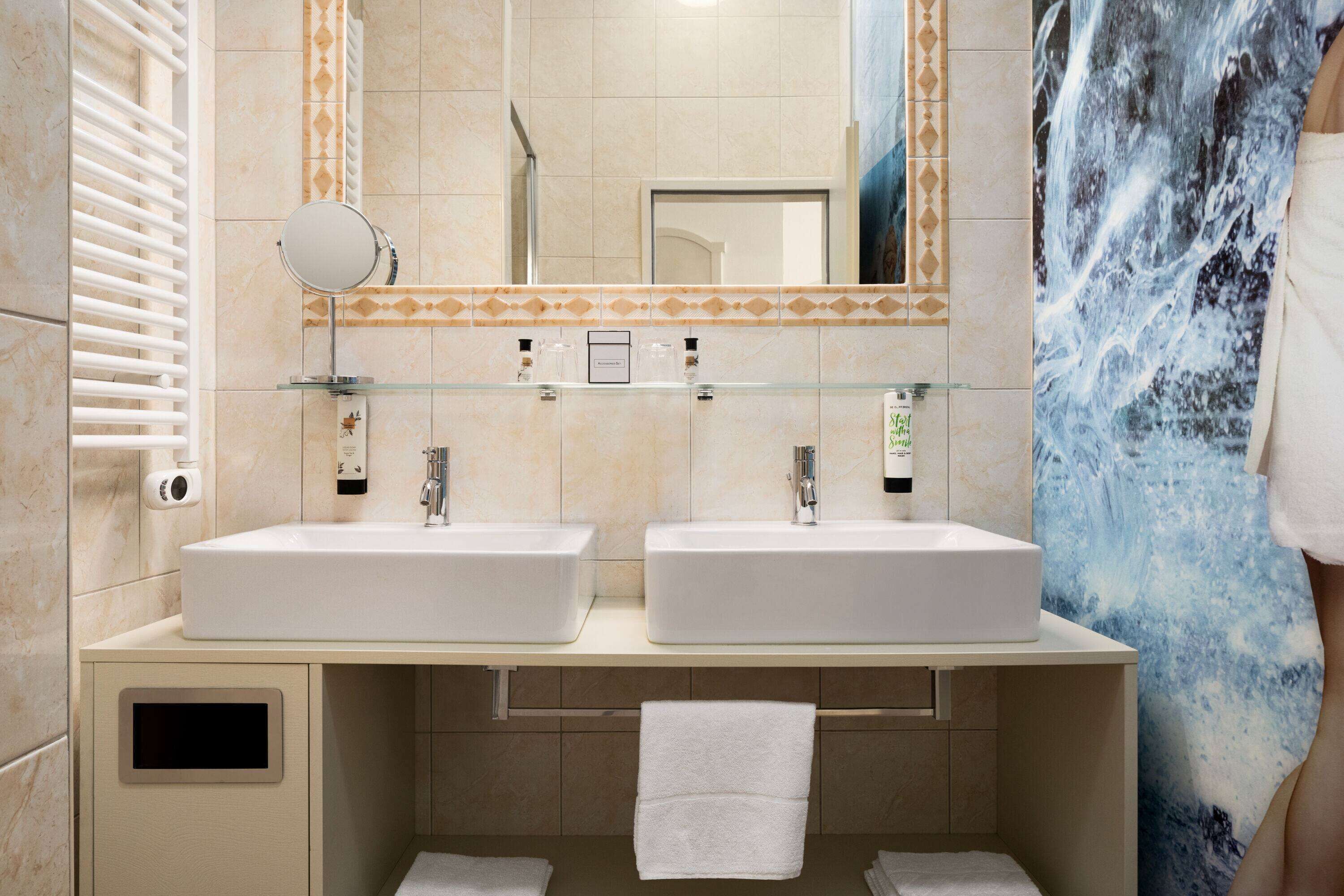 Une salle de bain avec deux lavabos, un miroir et un porte-serviettes.