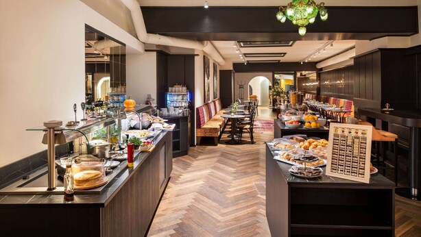 A hotel breakfast area with a buffet, seating, and a chandelier. - DORMERO PaHo Wels (Wels)