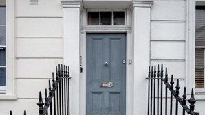 A white building with a blue door, black iron railings, and a set of stone steps leading to the entrance. - Stunning 2 Bedroom Duplex Apt in Center of Camden (London)
