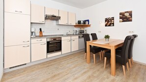Una cocina moderna con armarios de colores claros, una mesa de comedor de madera y sillas negras.
