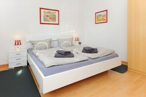 Quarto bem organizado com cama, mesas de cabeceira e duas fotografias emolduradas na parede.
