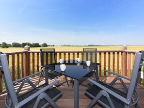 A deck with a glass table and chairs, overlooking a field. - Apartment starboard (Wittmund)