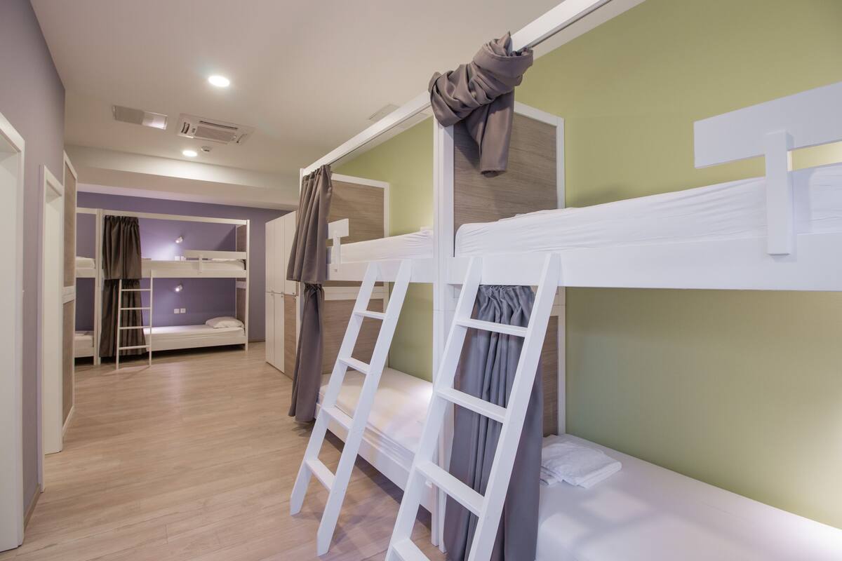 A room with bunk beds, a ladder, and a curtain.