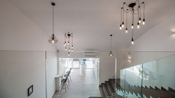 A modern interior with a staircase, glass railings, and hanging light fixtures. - Dandelion boutique hostel (Zadar)