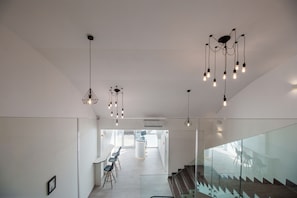 Ein modernes Interieur mit Treppe, Glasgeländern und Pendelleuchten.