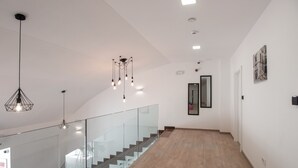 A modern interior with a staircase, glass railings, and contemporary lighting fixtures. - Dandelion boutique hostel (Zadar)
