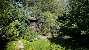 Un chalet isolé, entouré d’une végétation luxuriante, avec un sentier bien tracé qui y mène.