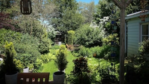 Un jardin agrémenté d’une pergola en bois, d’une petite structure en bois et d’un banc.