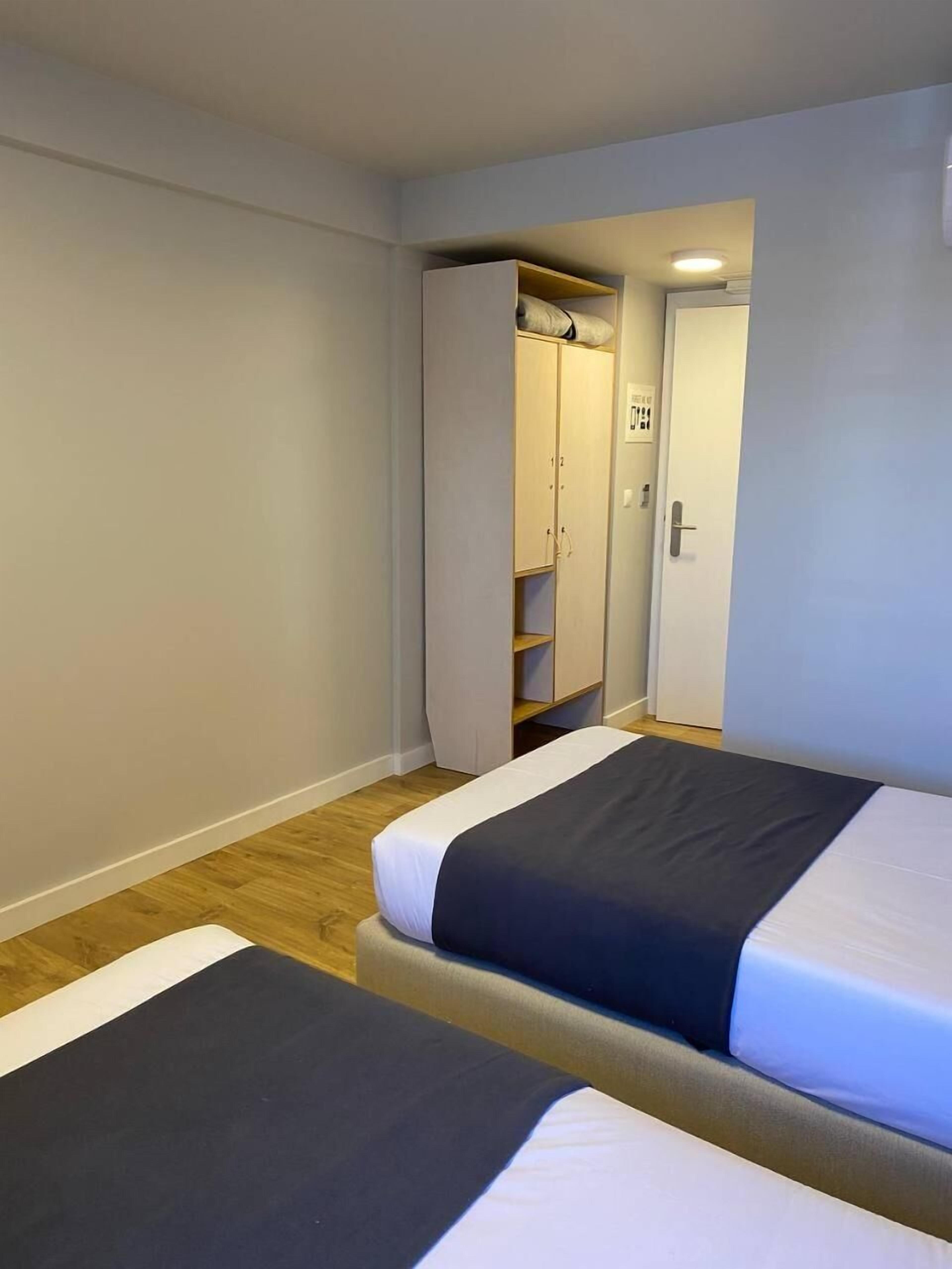 Une chambre avec deux lits, une armoire et une porte donnant sur une salle de bain.