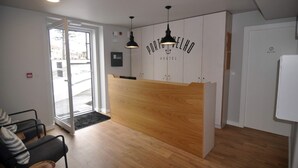 Een receptiebalie met een houten afwerking, een zwarte hanglamp en een bordje met de tekst 'Porto Velho Hostel'.