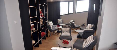 Un salon moderne avec une étagère noire, des canapés gris et des tables basses rondes.