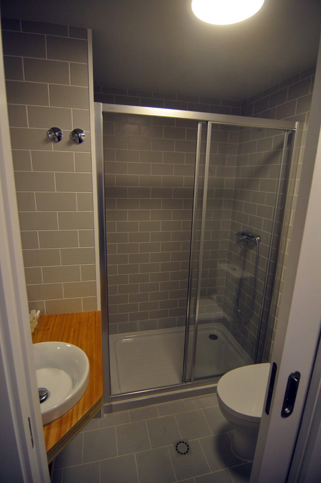 A modern bathroom with a glass shower enclosure, a wooden vanity, and a white sink.