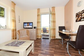 Una sala de estar moderna con piso de madera, un sofá, una mesa de comedor y un televisor.