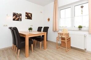 Un coin repas avec une table et des chaises en bois, une petite plante et une fenêtre donnant sur un beau paysage.