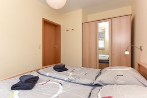 Une chambre avec deux lits, une armoire et un miroir.