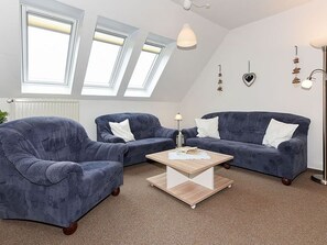 Un salon moderne avec deux canapés bleu foncé, une table basse en bois et un radiateur blanc.