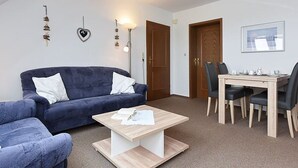 Un salon avec un canapé bleu, une table basse en bois et un coin repas comprenant une table et des chaises.