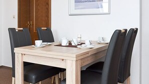 Une table à manger avec six chaises noires, des assiettes blanches et des tasses.