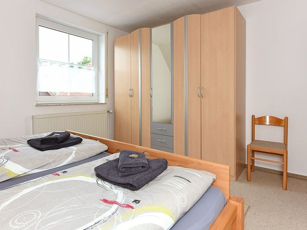 Ein Schlafzimmer mit zwei Betten, einem Kleiderschrank, einem Sessel und einem Fenster.