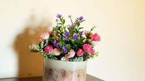 Ein Holztisch mit einer weißen Vase und einem Blumenarrangement.