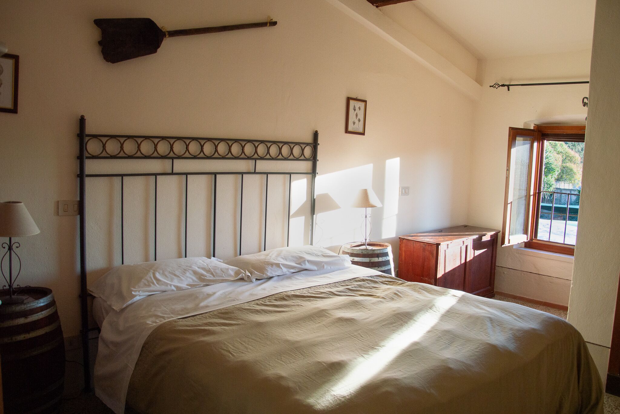 Un dormitorio con una cama, una mesita de noche de madera, una lámpara, una ventana y un estante en la pared.