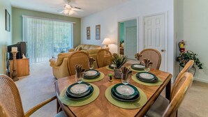 A dining area with a wooden table set for four, surrounded by wicker chairs.