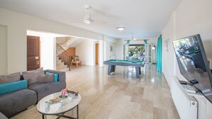 A spacious living room with a pool table, a sofa, a television, and a staircase leading to another room. - Luxury 4 Bedroom Villa With Private Pool, Sotira Villa 1301 (Sotira)