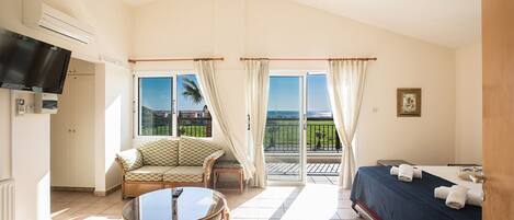 A hotel room with a balcony, a television, a dining table, and a bed.