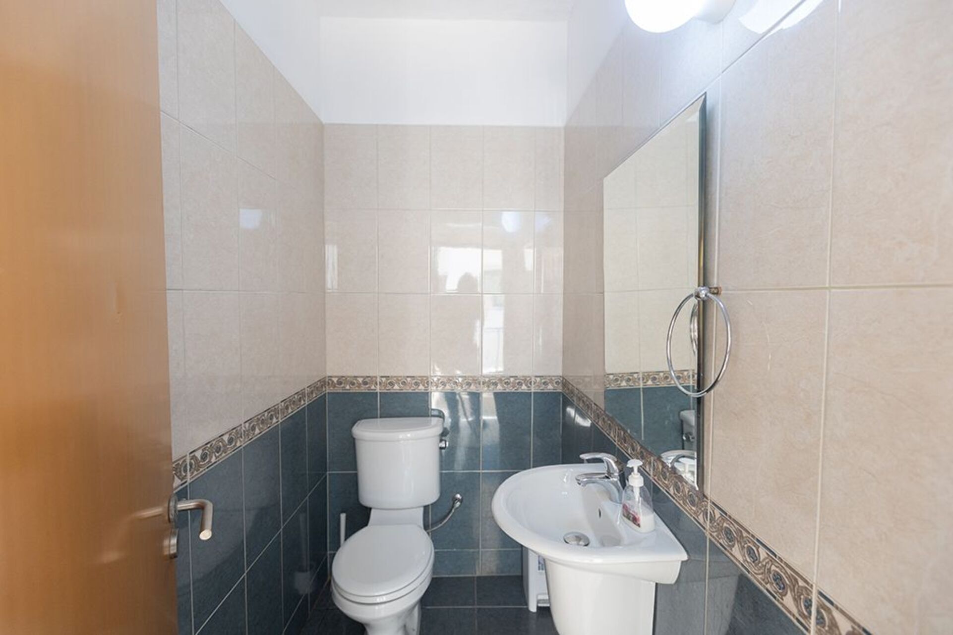 A bathroom with a toilet, sink, and mirror.