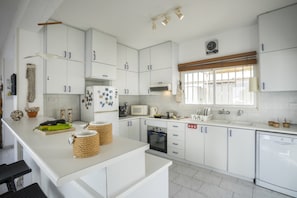 Cozinha moderna com armários brancos, micro-ondas, forno e pia.