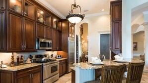 A kitchen with wooden cabinets, stainless steel appliances, a granite countertop, and a dining area with chairs.