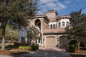 A two-story house with a garage, a balcony, and a large arched window. - Villa in Reunion Resort & Spa 1594 (Kissimmee)