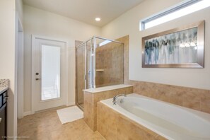Ein Badezimmer mit bodengleicher Dusche, einer Badewanne und einem großen Spiegel.