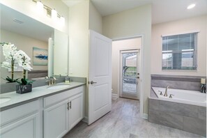 A modern bathroom with a double sink vanity, a large mirror, and a bathtub. - Luxury 8 Bedroom Villa on Champions Gate Resort, Orlando Villa 3584 (Davenport)