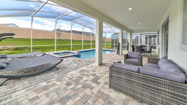 Un patio cubierto con piscina, mobiliario exterior y vistas del entorno.