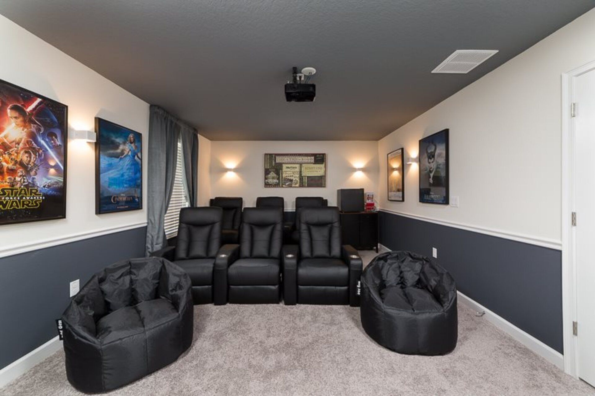 A home theater room with a projector, reclining chairs, bean bag seats, and movie posters on the walls.