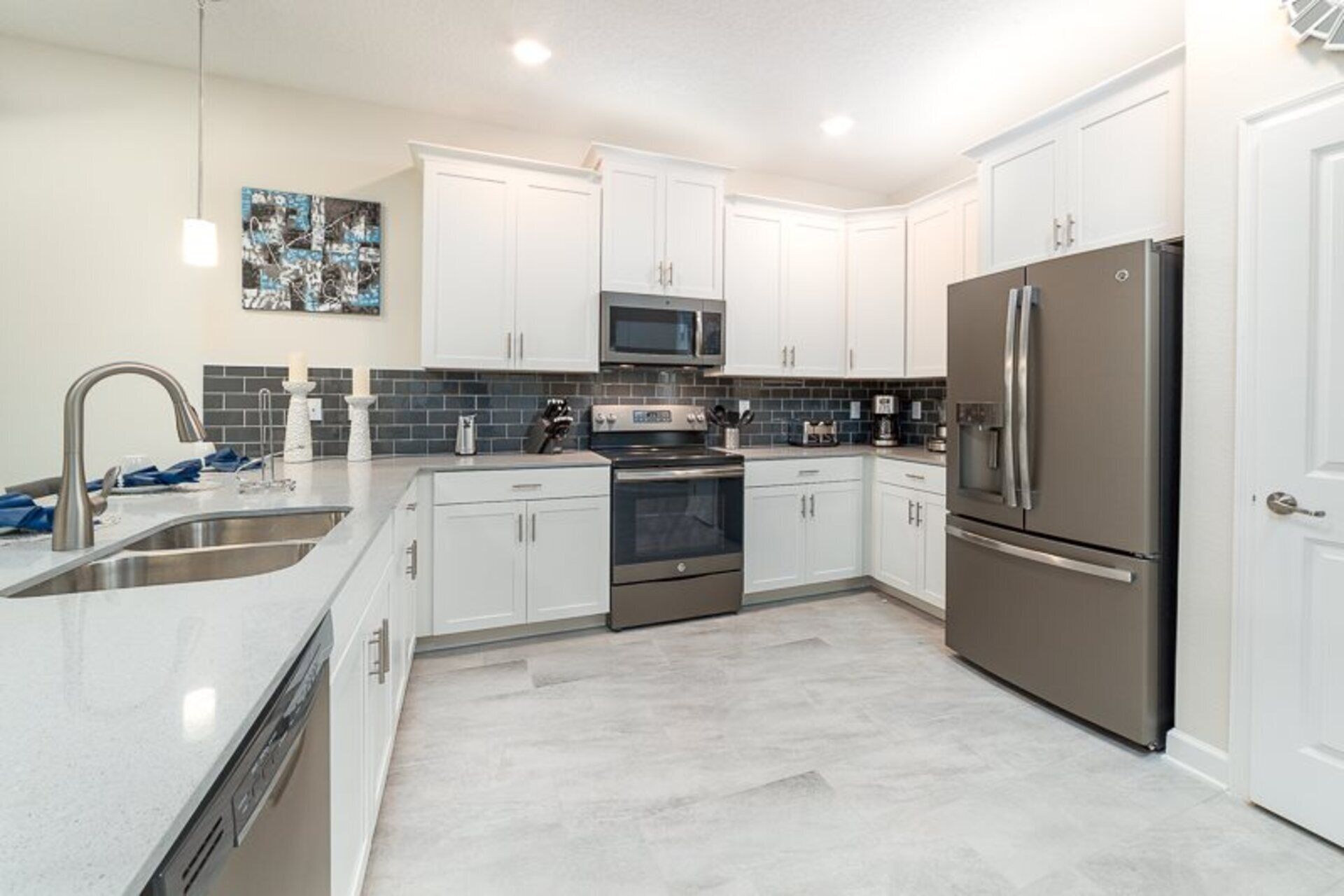 A modern kitchen with white cabinets, stainless steel appliances, and a tiled backsplash.