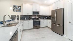 Una cocina moderna con armarios blancos, electrodomésticos de acero inoxidable y salpicadero de azulejos.