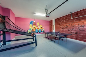 Une table de ping-pong dans une pièce dont un mur est rose et qui est décorée de graffitis.