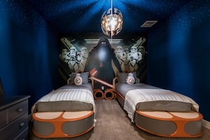 Une chambre avec deux lits, une fresque murale sur le thème de Star Wars et un luminaire sphérique original.
