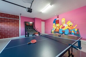 Une table de ping-pong équipée d’un projecteur et ornée d’une fresque représentant les personnages des « Simpsons ».